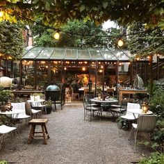 an outdoor dining area with tables and chairs, surrounded by greenery in the background