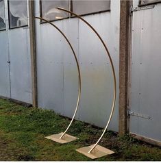 two metal sculptures sitting in the grass near a building