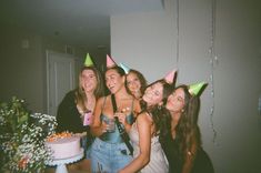 a group of young women standing next to each other in front of a birthday cake