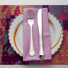 a plate with two silverware on it next to a purple and yellow napkin that has an orange border