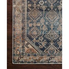 a blue and beige rug with an intricate design on the bottom, in front of a wooden