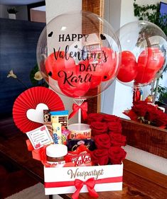 a valentine's day gift basket with balloons, candy and flowers on a table