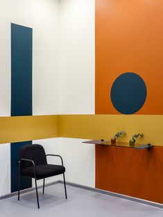 a chair sitting in front of an orange and blue wall