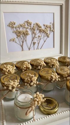 there are many jars with flowers in them on the table next to a framed photograph