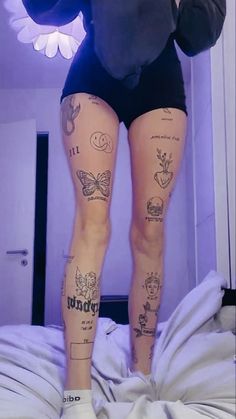 a woman with tattoos on her legs standing in front of a mirror