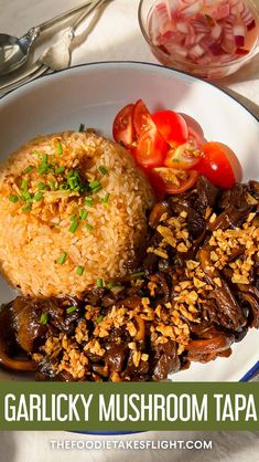 a white plate topped with meat and rice next to a bowl of vegetables on a table