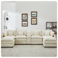 a living room with white couches and pictures on the wall