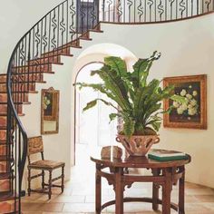 there is a potted plant on the table in front of the spiral stair case