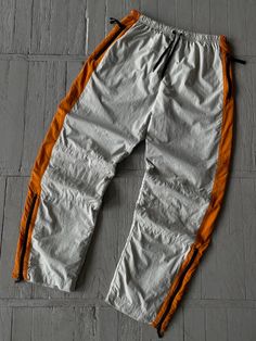 FOLLOW MY SHOP TO CHECK DAILY UPDATES & PRICE DROPS Vintage Nike Nylon Track Pants in Gray Orange Baggy relaxed fit. Y2K style. Wide leg. Elastic waist. Pockets on the waist. Small swoosh embroidered on the upper part of the Left leg Size L Waist (1/2) - 14.5'' Length - 32'' Leg Opening - 9'' Pants are in very good pre-owned condition. Please check pictures for more information on the product Shipping options: - standard shipping in 7-15 days - priority in 3-5 business days (price will be more)   Check out my other items & follow - new arrivals every week! If you have any questions regarding the item, shipping - feel free to contact any time. All items are genuine. Customer satisfaction is our priority! Nylon Track Pants, Fit Y2k, Nike Vintage, Waist Small, Y2k Style, Vintage Nike, Track Pants, Halloween Shopping, Elastic Waist