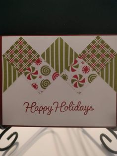 a happy holiday card hanging from a metal hook on a wall with the words happy holidays written in red, green and white