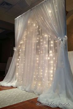 a bed with white curtains and lights on the headboard is set up for a wedding