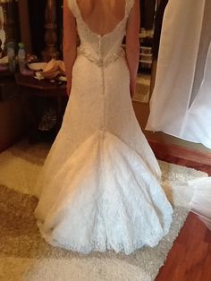 a woman in a wedding dress is standing on the floor with her back to the camera