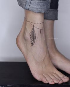 a woman's foot with a small feather tattoo on the side of her ankle