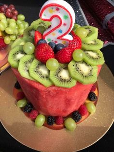 a birthday cake made to look like fruit with the number 2 on top and two candles in the middle