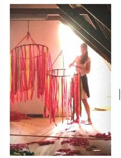 a woman standing in front of a red and yellow dream catcher hanging from the ceiling