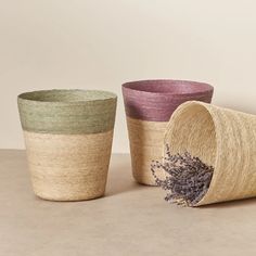 three different colored baskets sitting next to each other on top of a table with lavenders in them