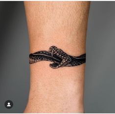 a black and white tattoo on the ankle of a man with a snake in it