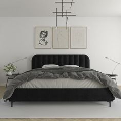 a bedroom with white walls and black bedding, two pictures on the wall above it