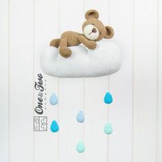 a crocheted teddy bear is laying on top of a cloud with rain drops