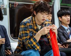 two young men sitting next to each other in front of a bus looking at something