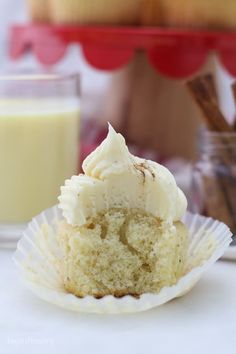 a cupcake sitting on top of a paper plate next to a glass of milk