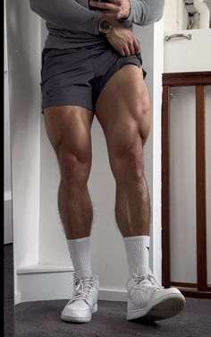 a man in shorts and socks standing with his legs crossed