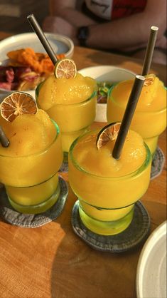 four glasses filled with orange juice and garnished with lemon wedges on a wooden table