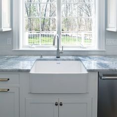 a white kitchen sink sitting under a window