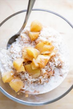 a glass bowl filled with oatmeal topped with sliced pineapple and coconut