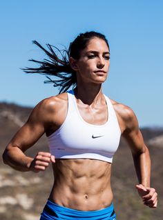 a woman running in a white top and blue skirt with her hair blowing in the wind