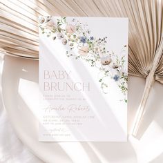 a baby brunch card on a plate next to an open book and fan