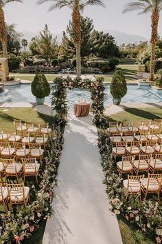 an outdoor ceremony setup with chairs, flowers and greenery at the end of the aisle