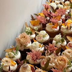 many cupcakes with flowers on them are lined up