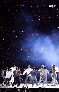 a group of people standing on top of a stage under a sky filled with stars