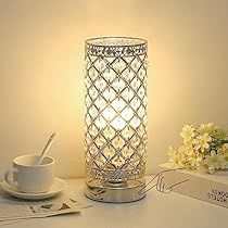 a white table topped with a cup and saucer next to a light on top of a box