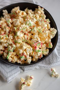 a bowl full of popcorn with sprinkles and candy canets on the side