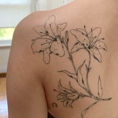 the back of a woman's shoulder with flowers tattooed on her left arm and chest