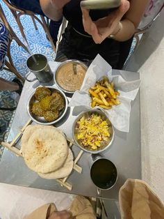 a person sitting at a table with many different foods in bowls and plates on it