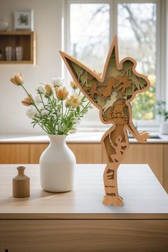 a vase with flowers sitting next to a cut out figure