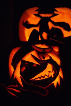 two carved pumpkins sitting on top of each other in the dark, with faces carved into them