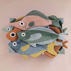 a group of fish sitting on top of each other in front of a pink wall