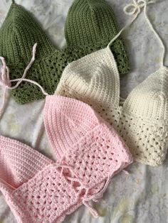 three crocheted hats and one knitted hat are laying on a bed together