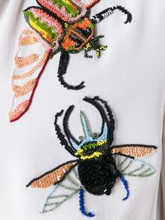 an embroidered insect on a white shirt with multicolored sequins