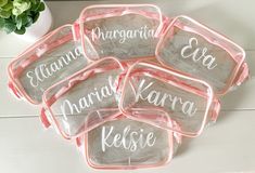 six personalized clear plastic trays on a white wooden table next to a potted plant