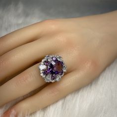 Details: Materials: Amethyst Gemstone, White Zircons, S925 Sterling Silver Plated with 18K White Gold Shape: Oval Size: Adjustable and fitable for all Descriptions: This oval shape design ring has one 12x10mm and six 3.5x3.5mm amethysts. The ring is made out of S925 sterling silver plated with 18K white gold. Surrounding the amethysts are twenty-four (24) white zircons, which make the amethysts stand out and shine. The arrangement of the amethysts makes it look like a flower shape from a distanc Ring Birthstone, Amethyst Gem, Purple Band, White Gold Ring, Amethyst Gemstone, Amethyst Ring, Shape Design, Flower Shape, White Gold Rings