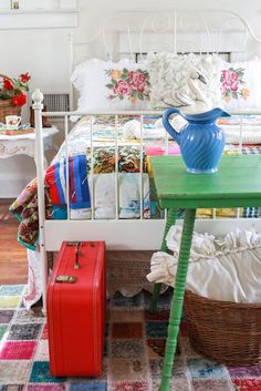 a bed with a green table and red suitcase next to it