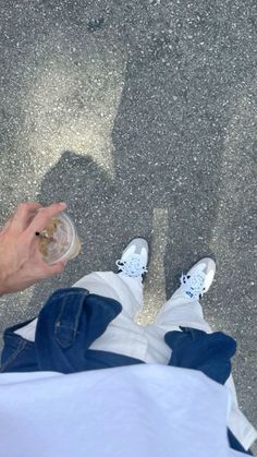 a person holding a wine glass in their hand while standing on the ground with his feet up