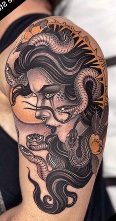 a woman with a dragon tattoo on her arm and shoulder, holding a snake in her hand