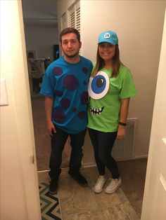 the man and woman are dressed up as monsters for halloween costumes, standing in front of an open door