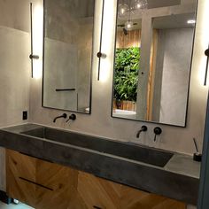 a bathroom with two sinks, mirrors and lights on the wall above it's counter